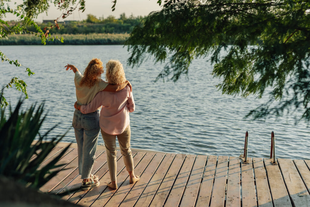 Mother and daughter stand arm in arm, enjoying a peaceful moment together in nature.